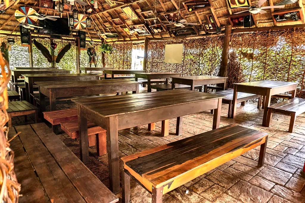 Comedor bajo palapa de Cancún Jungle Camp con mesas y bancas largas de madera
