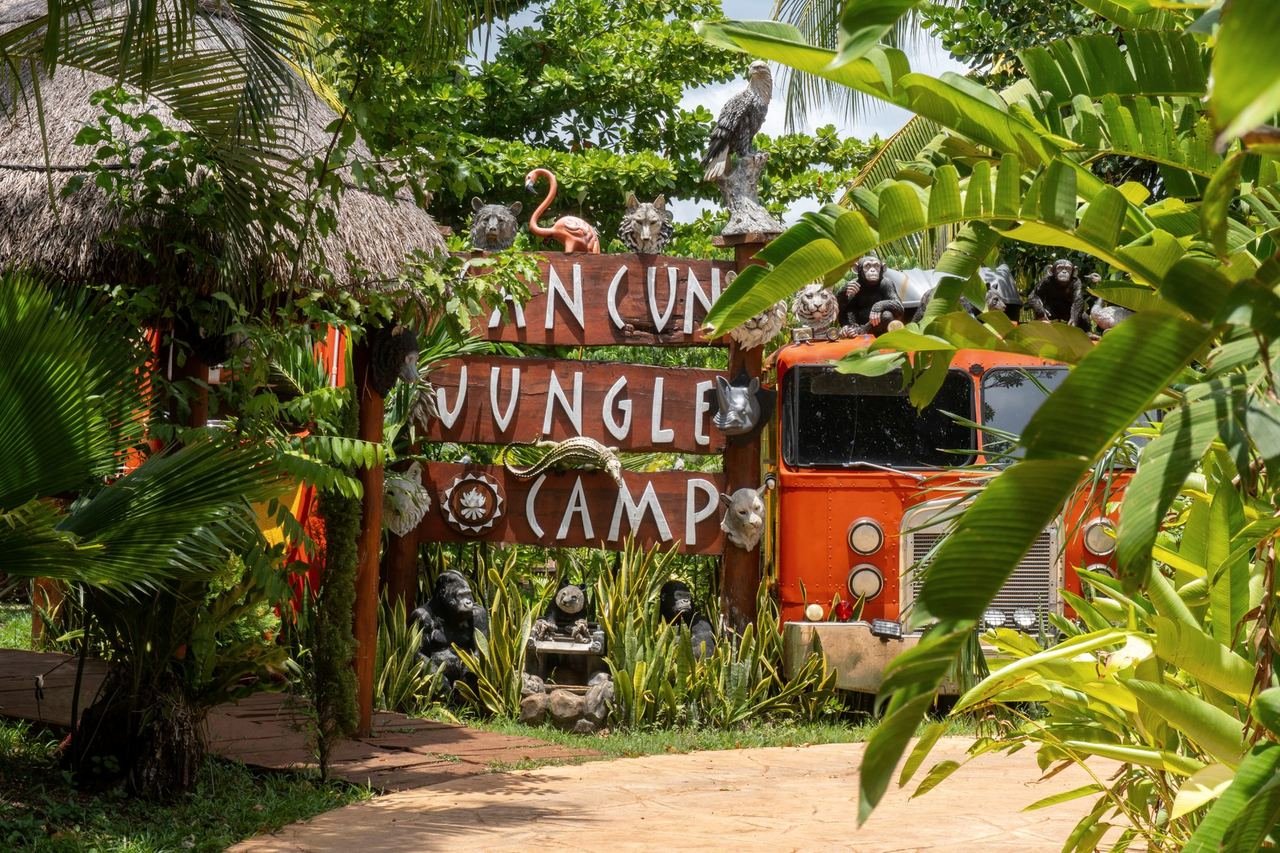 Entrada del campamento con el letrero de madera y el camión