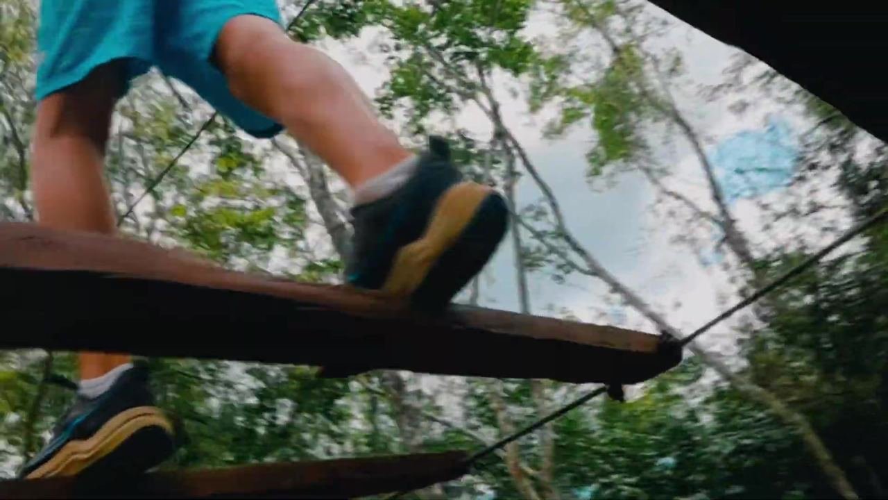 Pies de una persona cruzando una viga de madera del circuito de retos
